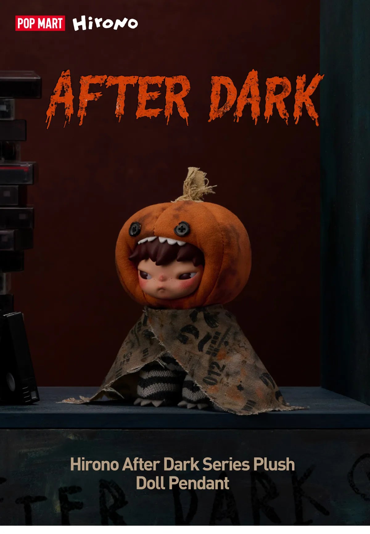 Hirono After Dark Series Plush Doll Pendant featuring a character in an orange pumpkin head costume with a distressed brown cape, displayed on a dark shelf against a dark background with 'AFTER DARK' text.